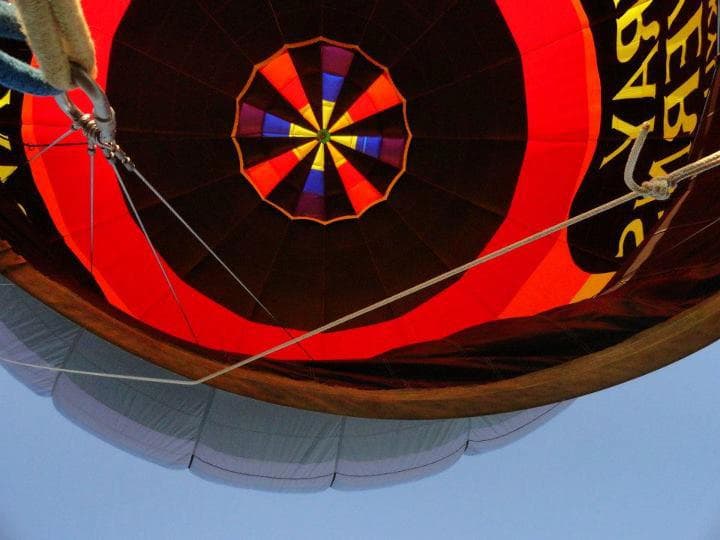 Upward view into a red and black hot air balloon with a rainbow pattern.